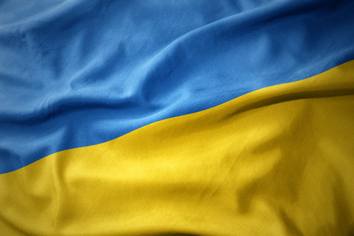 KI generiert: Das Bild zeigt eine Nahaufnahme einer Flagge mit zwei horizontalen Streifen: oben blau und unten gelb. Es handelt sich um die Nationalflagge der Ukraine.