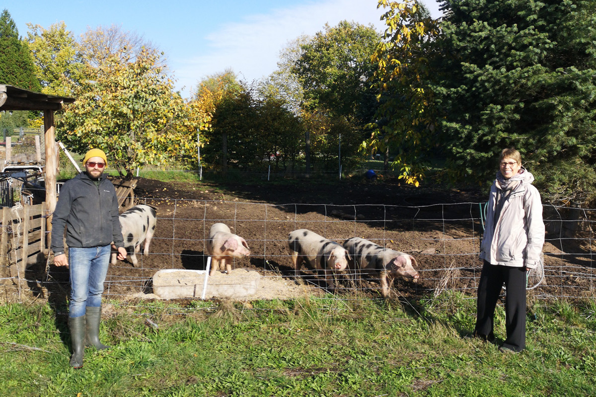 Foto von Dorothea Frederking mit einem Landwirt. Im Hintergund sieht man Schweine.  