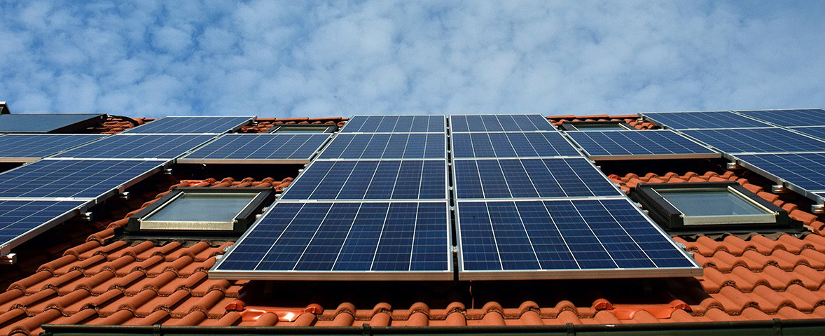 KI generiert: Das Bild zeigt Solarzellen, die auf dem Dach eines Gebäudes montiert sind. Sie sind auf roten Ziegeln installiert und reichen über mehrere Dachfenster.