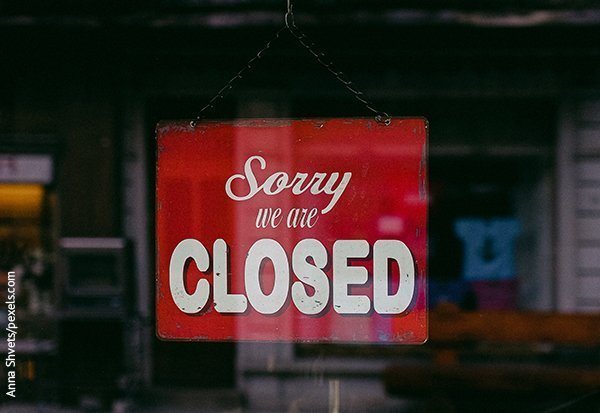 Ein Schild mit der Aufschrift "Sorry we are closed" hängt an der Landentür eines Geschäfts. 