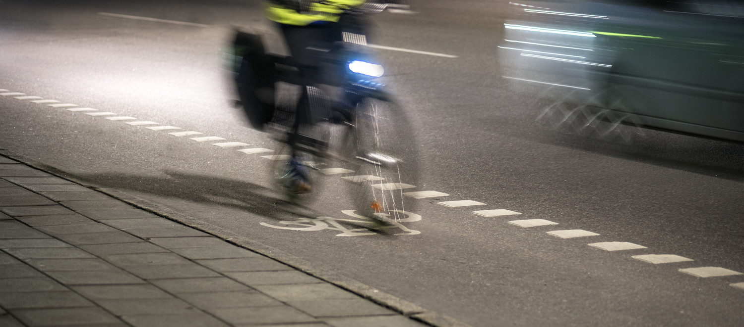 KI generiert: Das Bild zeigt einen Radfahrer, der in der Nacht mit eingeschaltetem Vorderlicht auf einem Fahrradweg fährt. Die Szene ist in Bewegung und auf einer Straße erkennbar.