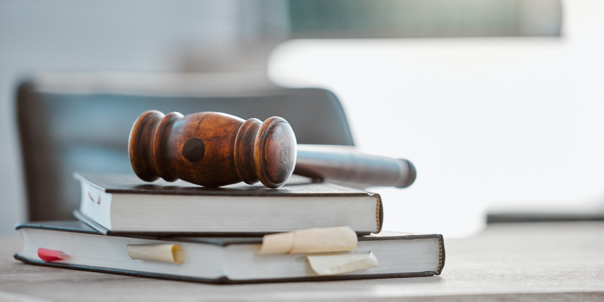 KI generiert: Das Bild zeigt einen Richterhammer, der auf einem Stapel von Büchern liegt. Dies symbolisiert Recht und Justiz.