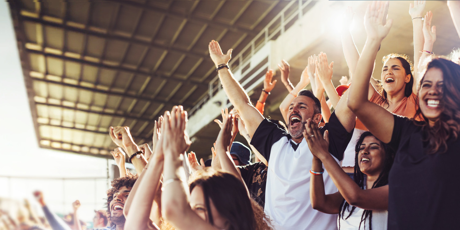 KI generiert: Das Bild zeigt eine jubelnde Menschenmenge im Stadion, die offensichtlich einen sportlichen oder anderen öffentlichen Event verfolgt. Die Fans wirken begeistert und heben die Arme in die Luft, was auf einen spannenden Moment hindeutet.