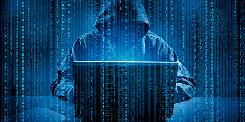 KI generiert: Das Bild zeigt eine Person mit Kapuze, die vor einem Laptop sitzt, während binärer Code den Hintergrund und den Vordergrund füllt. Es vermittelt den Eindruck von Cyberkriminalität oder Hacking.