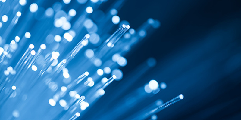 KI generiert: Das Bild zeigt blau beleuchtete Glasfasern in Nahaufnahme. Die Fasern sind unscharf im Hintergrund und erzeugen ein modernes, technologisches Gefühl.